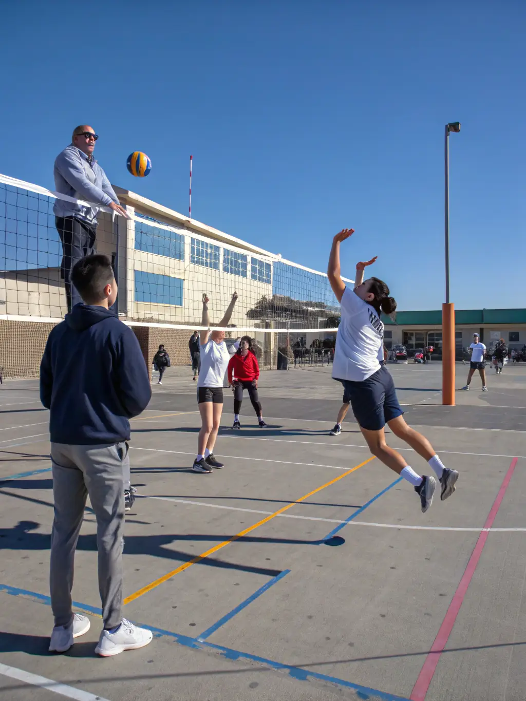 A diverse group of students participating in a volleyball game, highlighting inclusivity and teamwork.
